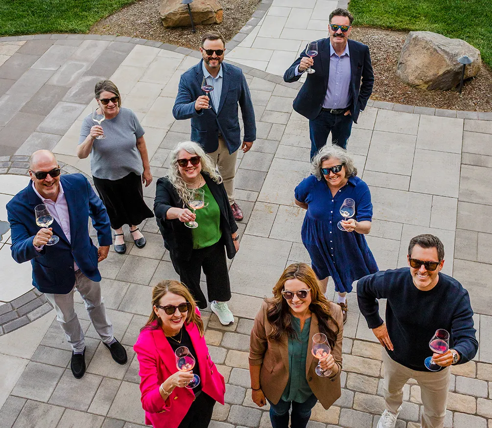 Group of people looking up and raising their wine glasses to toast.