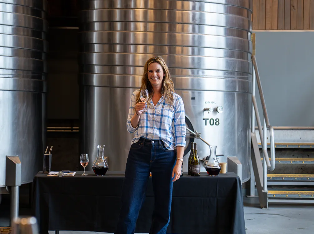 Lady standing in a winery holding a glass of wine.